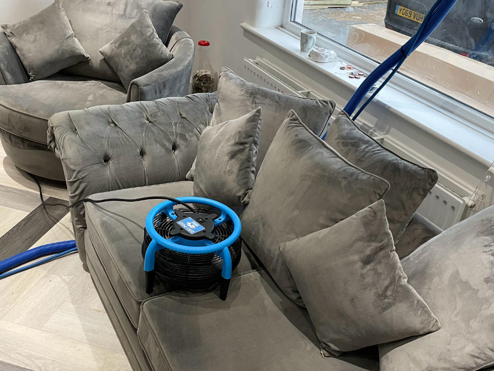 A freshly cleaned couch drying with the help of a fan